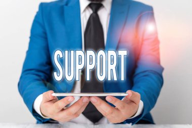 Kelime yazma desteği. Katılıyor ve teşvik ediyor. Mavi süitte dizüstü bilgisayarı elinde tutan bir iş adamı..