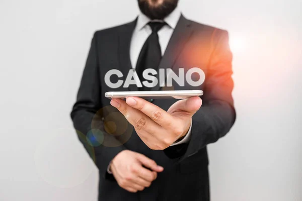 Handwriting text writing Casino. Concept meaning a building where games especially roulette and card games are played Male human wear formal work suit hold smart hi tech smartphone use one hand. — Stok fotoğraf