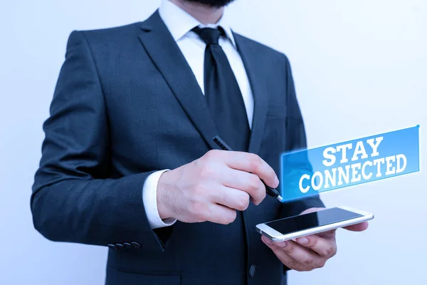 Text sign showing Stay Connected. Conceptual photo To keep communicating on each other To retain in touch Male human wear formal work suit hold smart hi tech smartphone use one hand. — Stock fotografie