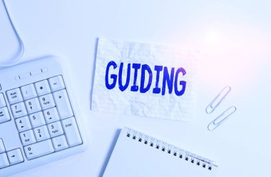 Handwriting text Guiding. Concept meaning to show someone how to do something difficult Indicate the way White pc keyboard with empty note paper above white background.