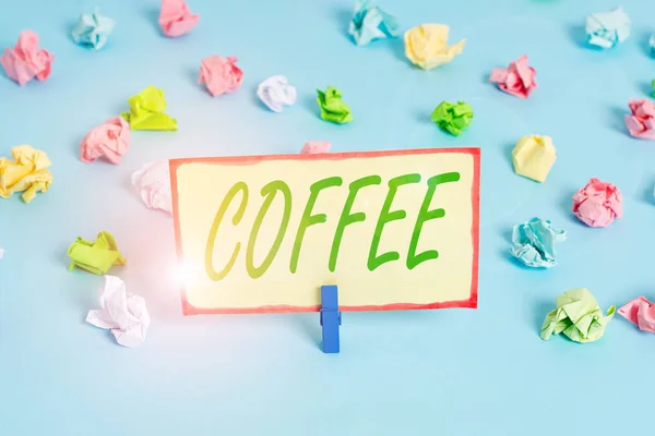 Writing note showing Coffee. Business photo showcasing hot drink made from the roasted and ground seeds of a tropical shrub Colored crumpled papers empty reminder blue floor background clothespin. — Stok fotoğraf