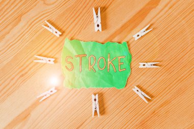 Felç belirtileri var. Kavramsal fotoğraf hastaları kan akışının kötü olması yüzünden bilincini kaybediyor. Renkli çamaşır mandalı kağıtları boş, ahşap zemin ofisini anımsatıyor..