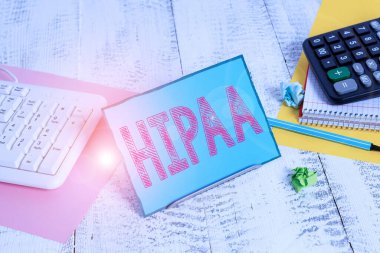Hipaa 'yı gösteren bir not yazıyorum. İş fotoğraflarının gösterildiği Kısaltma, Sağlık Sigortası Taşınabilirlik Hesabının bilgisayar klavyesi ve sayfaları arasında tel üzerine not defteri anlamına geliyor.