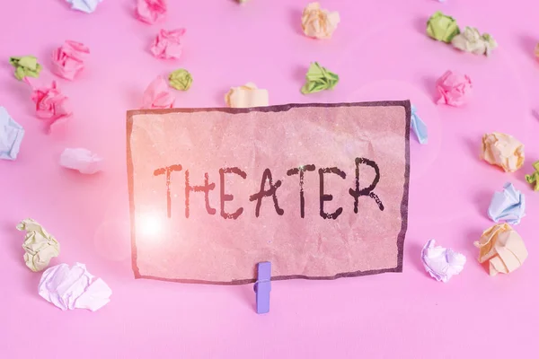 Χειρόγραφο κείμενο που γράφει Θέατρο. Έννοια σημαίνει κτίριο ή εξωτερικό χώρο στον οποίο παίζει και δραματικές διατρήσεις Χρωματιστά τσαλακωμένα χαρτιά κενό υπενθύμιση ροζ φόντο clothespin. — Φωτογραφία Αρχείου