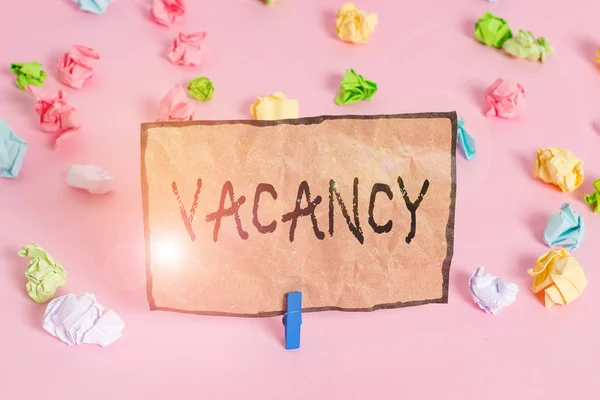 Handwriting text writing Vacancy. Concept meaning available paid place in small or big company State of being vacant Colored crumpled papers empty reminder pink floor background clothespin.