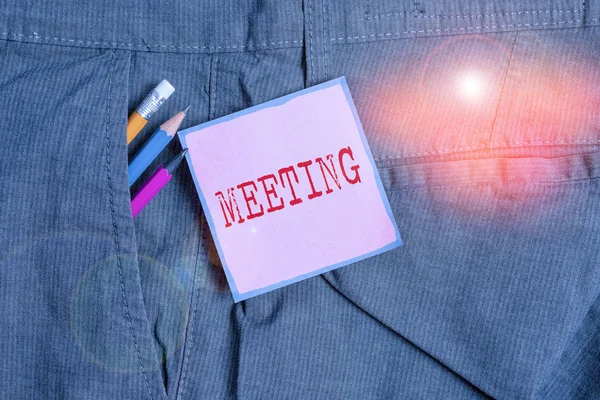 Handwriting text writing Meeting. Concept meaning assembly of showing for a particular purpose or for formal discussion Writing equipment and pink note paper inside pocket of man work trousers. — Stockfoto