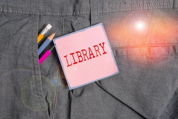 Skriva handstil bibliotek. Begreppet mening Byggrum med boksamlingar Studieplats Skrivutrustning och rosa anteckningspapper inuti fickan på arbetsbyxor för män. — Stockfoto