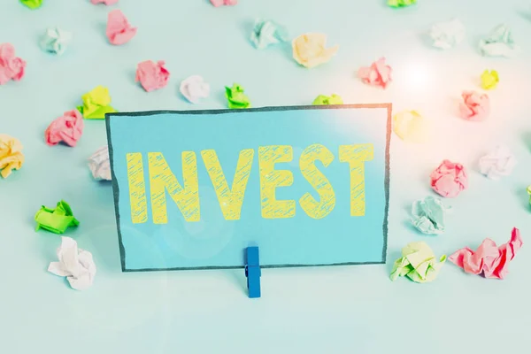 Scrivere una nota che mostra Invest. Business photo vetrina impresa commerciale con l'aspettativa di raggiungere un profitto Colorato carta spiegazzata vuoto promemoria blu pavimento sfondo molletta . — Foto Stock