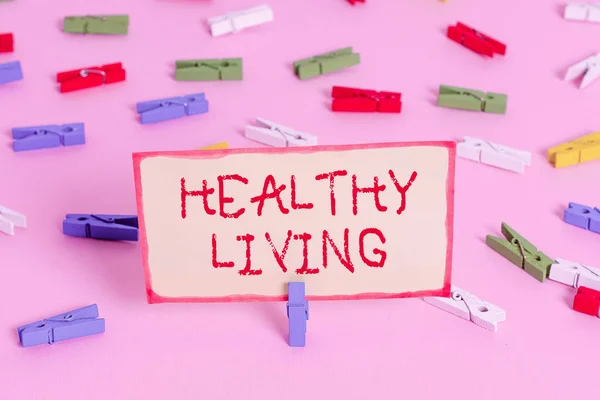 "Sağlıklı Yaşam" el yazısı. Ciddi şekilde hasta olma riskini azaltan bir yaşam biçimi kavramı. Renkli çamaşır iğnesi kağıtları boş. Pembe zemin ofis broşu.. — Stok fotoğraf