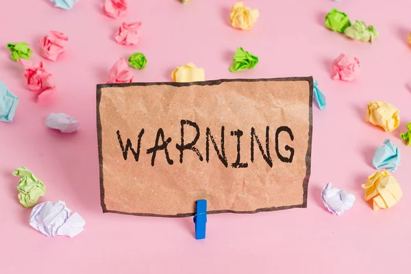 Handwriting text writing Warning. Concept meaning Advice Sign for possible danger Safety symbol Caution alert Colored crumpled papers empty reminder pink floor background clothespin. — Stok fotoğraf