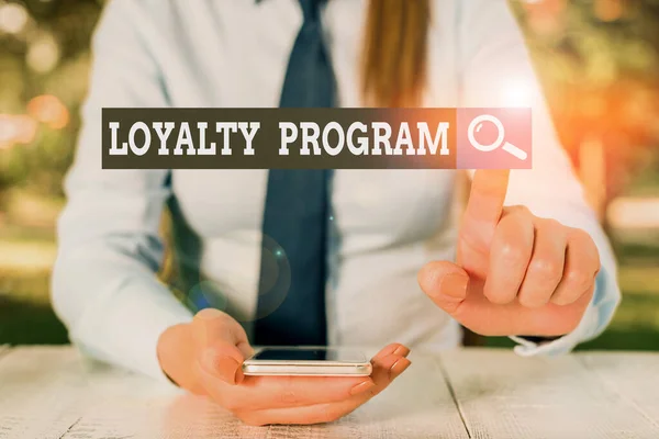 Text sign showing Loyalty Program. Conceptual photo marketing effort that provide incentives to repeat customers Female business person sitting by table and holding mobile phone.
