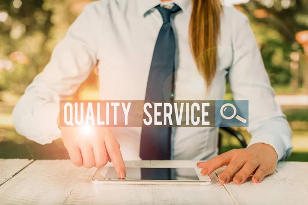 Writing note showing Quality Service. Business photo showcasing delivered service conforms to the client s is expectations Female business person sitting by table and holding mobile phone. — Stockfoto