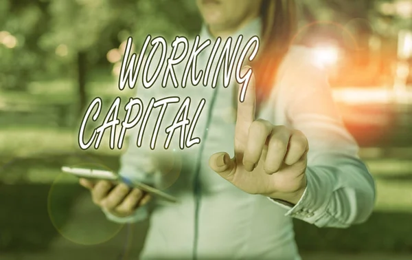 Text sign showing Working Capital. Conceptual photo money available to a company for day to day operations Woman in a blue business shirts pointing with her finger into empty space.