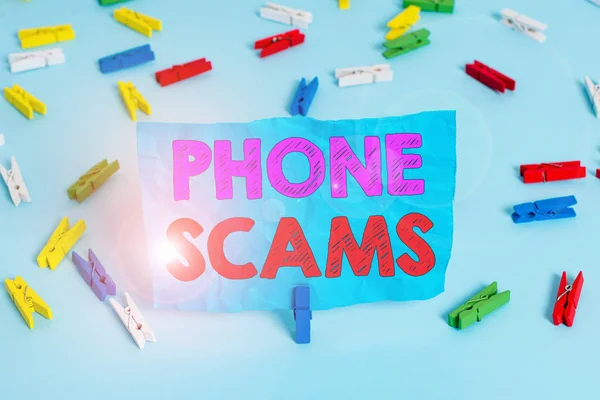 Word writing text Phone Scams. Business concept for use of telecommunications for illegally acquiring money Colored clothespin papers empty reminder blue floor background office pin. — Stockfoto