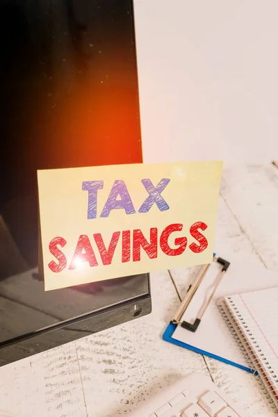 Text sign showing Tax Savings. Conceptual photo only a portion of income is taxable Pay a reduced amount of tax Note paper taped to black computer screen near keyboard and stationary. — Zdjęcie stockowe