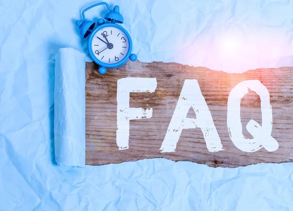 Word writing text Faq. Business concept for A list of questions and answers relating to a particular subject Alarm clock and torn cardboard placed above a wooden classic table backdrop. — Φωτογραφία Αρχείου