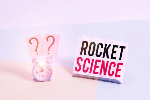 Writing note showing Rocket Science. Business photo showcasing difficult activity that you need to be intelligent to do Alarm clock beside a Paper sheet placed on pastel backdrop. — Φωτογραφία Αρχείου