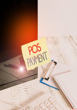 Pos Ödeme 'yi gösteren bir not yazıyorum. İş fotoğrafı gösteren müşteri, mal ve hizmetler karşılığında ödemeyi sunuyor. Klavye yakınındaki siyah bilgisayar ekranına yapıştırılmış not kağıdı..