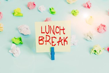 Kelime yazma öğle yemeği molası. Bir gösterinin çalışmayı bırakması ya da öğle yemeği yemek için çalışmayı bırakması için iş konsepti. Renkli buruşmuş kağıtlar boş mavi zemin çamaşır mandalı..