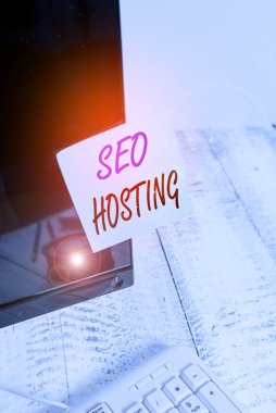 Seo Sunucu 'nun el yazısı. Konsept, arama motorları için kullanışlı bir web sitesi oluşturma anlamına gelir. Not kağıdı beyaz klavyenin yanındaki siyah bilgisayar monitörü ekranına yapıştırılmıştır..
