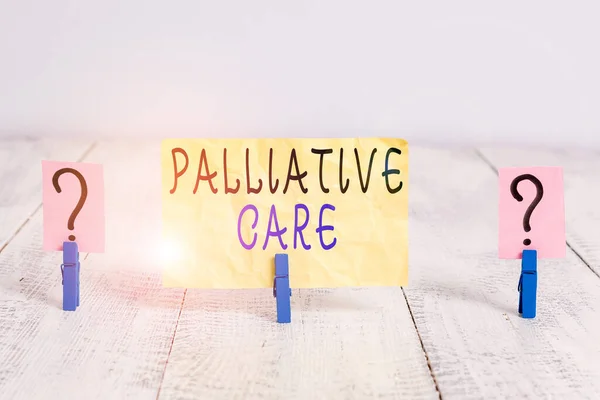 Writing note showing Palliative Care. Business photo showcasing specialized medical care for showing with a serious illness Crumbling sheet with paper clips placed on the wooden table.