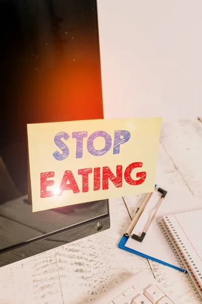 Sinal de texto mostrando Pare de comer. Foto conceitual cessar a atividade de colocar ou tomar alimentos na boca Nota papel colado à tela do computador preto perto do teclado e estacionário . — Fotografia de Stock