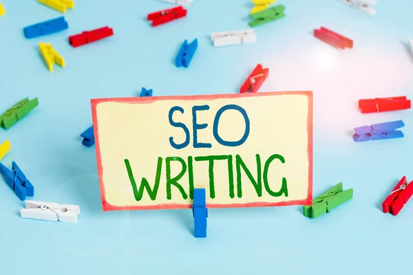 Handwriting text Seo Writing. Concept meaning grabbing the attention of the search engines using specific word Colored clothespin papers empty reminder blue floor background office pin. — Stockfoto