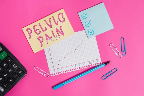 Handwriting text writing Pelvic Pain. Concept meaning Pain perceived in the area of the lower part of the abdomen Stationary and note paper plus math sheet with diagram picture on the table.