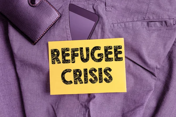 Word writing text Refugee Crisis. Business concept for refer to movements of large groups of displaced showing Smartphone device inside trousers front pocket with wallet and note paper.