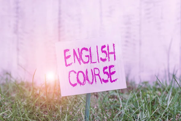 Text sign showing English Course. Conceptual photo courses cover all levels of speaking and writing in english Plain empty paper attached to a stick and placed in the green grassy land.