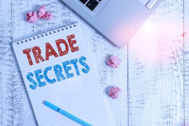 Ticaret Sırları 'nı gösteren kavramsal el yazısı. Ürünlerini üretirken bir şirket tarafından kullanılan iş fotoğrafı sergisi tekniği dizüstü bilgisayarın yönettiği spiral not defteri kağıt topları ahşap masa..