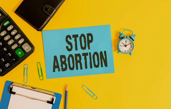 Signo de texto que muestra Stop Abortion. Foto conceptual para detener el procedimiento médico que solía terminar un embarazo Clipboard clips hoja calculadora lápiz despertador reloj billetera color fondo . — Foto de Stock