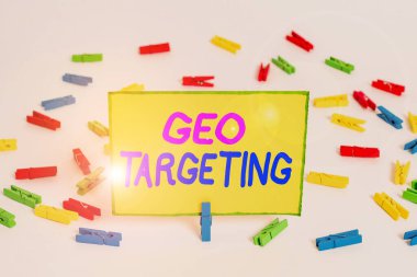 Writing note showing Geo Targeting. Business photo showcasing method of determining the geolocation of a website visitor Colored clothespin papers empty reminder white floor background office.
