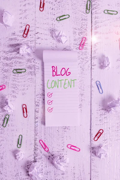 Conceptual hand writing showing Blog Content. Business photo showcasing Posts on one continuous streaming page or individual pages Stripped ruled notepad clips paper balls wooden background.