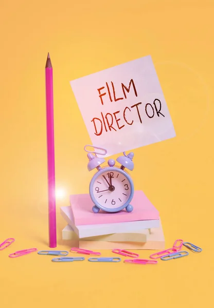 Writing note showing Film Director. Business photo showcasing a demonstrating who is in charge of making and directing a film Alarm clock sticky note stacked notepads pencil colored background. — 스톡 사진