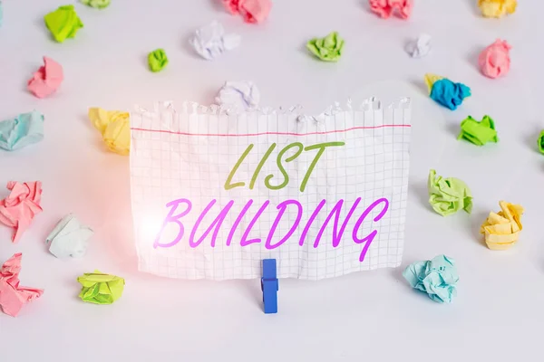 Handwriting text writing List Building. Concept meaning database of showing you can contact with your marketing message Colored crumpled papers empty reminder white floor background clothespin.