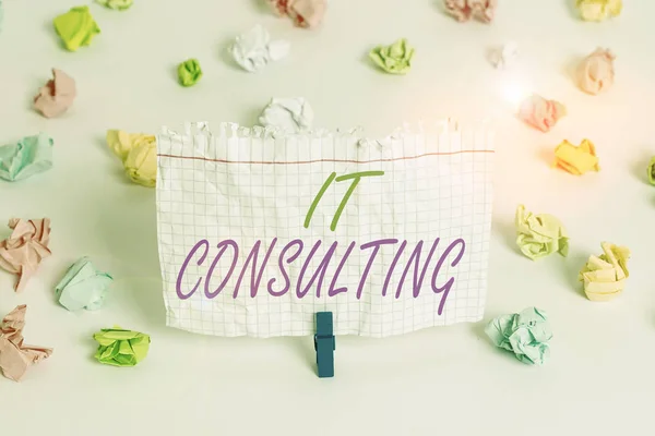 Handwriting text writing It Consulting. Concept meaning Focuses on advising organizations hot to manage their IT Colored crumpled papers empty reminder white floor background clothespin. — Stockfoto