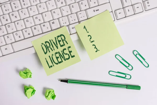 Handwriting text writing Driver License. Concept meaning a document permitting a demonstrating to drive a motor vehicle Square green note paper with pencil on the white background.
