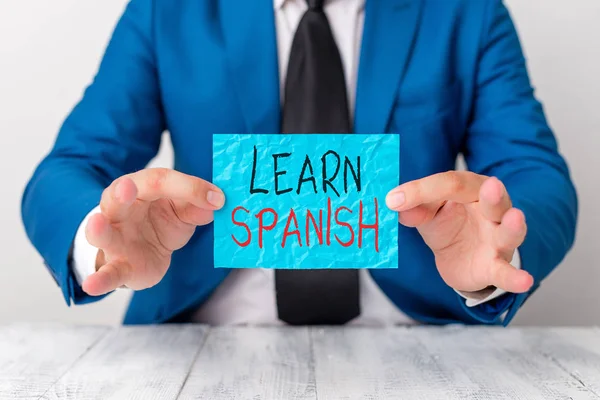 Text sign showing Learn Spanish. Conceptual photo gain or acquire knowledge of speaking and writing Spanish Man holds empty paper with copy space in front of him Copy Space. — Stok fotoğraf