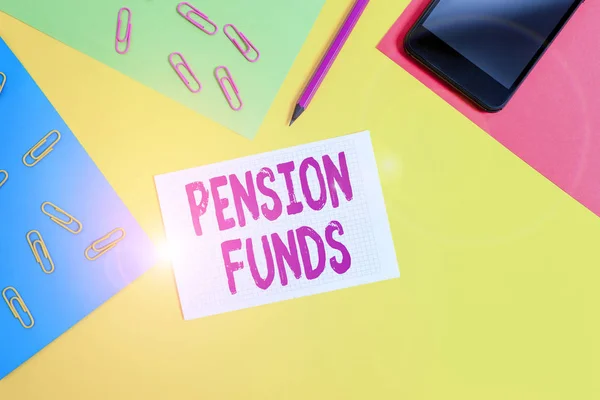 Handwriting text writing Pension Funds. Concept meaning investment pools that pay for employee retirement commitments Paper sheets pencil clips smartphone squared notebook colored background.