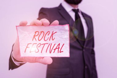 Writing note showing Rock Festival. Business photo showcasing Largescale rock music concert featuring heavy metals genre Male human wear formal work suit with office look hold book.