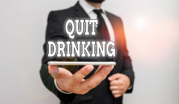 Handwriting text writing Quit Drinking. Concept meaning involves staying away from consuming alcoholic beverages Male human wear formal work suit hold smart hi tech smartphone use one hand.