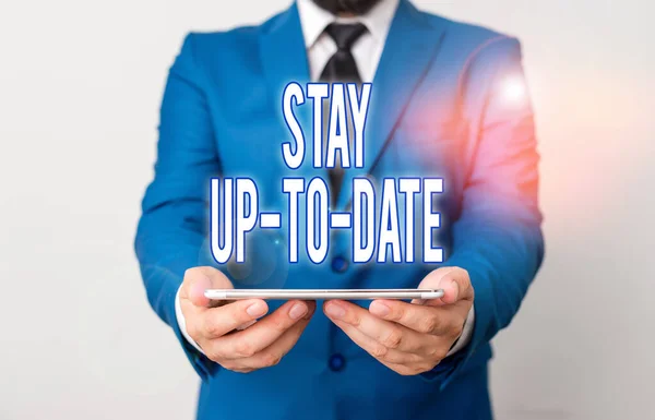 Word writing text Stay Up To Date. Business concept for knows all the most recent news and changes in a situation Businessman in blue suite with a tie holds lap top in hands.