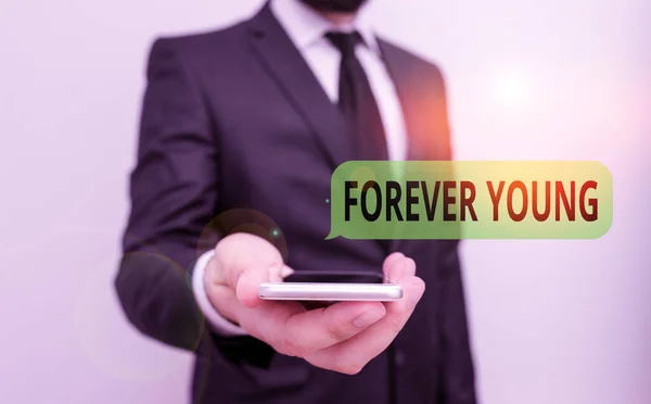 Текст слова Forever Young. Бизнес-концепция для мышления быть свежим и свежим вне зависимости от возраста Мужчины носить формальный рабочий костюм держать умный высокотехнологичный смартфон использовать одной рукой . — стоковое фото