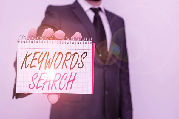 Text sign showing Keywords Search. Conceptual photo looks for matching documents that contain one or more words Male human wear formal work suit office look hold mathematics book use hand. — Stockfoto