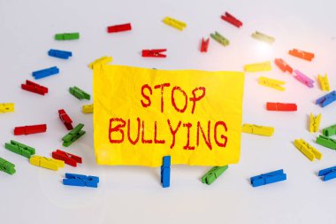 Word writing text Stop Bullying. Business concept for stop the aggressive behaviour among school aged children Colored clothespin papers empty reminder white floor background office.
