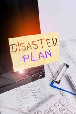 Conceptual hand writing showing Disaster Plan. Business photo showcasing outlines how an organization responds to an unplanned event Note paper taped to black screen near keyboard stationary. clipart
