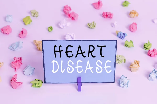 Text sign showing Heart Disease. Conceptual photo class of diseases that involve the heart or blood vessels Colored crumpled papers empty reminder white floor background clothespin. — Stock Photo, Image