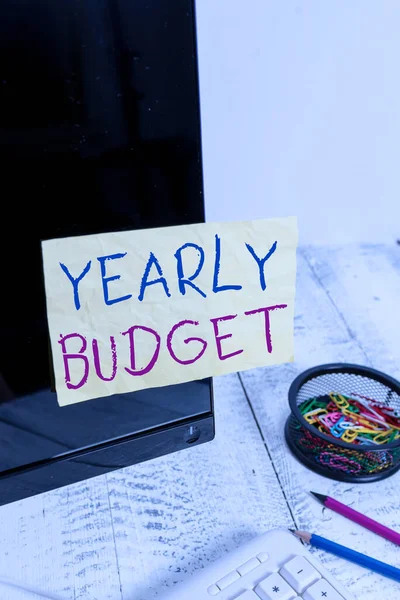 Az éves költségvetést mutató szöveges tábla. Fogalmi fotó A terv a vállalati kiadások egy pénzügyi évre Megjegyzés papír ragasztva fekete számítógép képernyő közelében billentyűzet és álló. — Stock Fotó