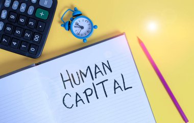 Huanalysis Capital 'i gösteren bir not yazıyorum. Bir işçinin ekonomik değerinin ölçüldüğü iş fotoğrafı gösterimi. Çizgili çizgili not defteri. Metal alarm saati arkaplan rengi..